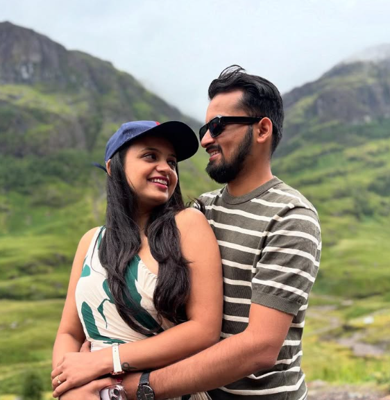 Anjali and Dhruv smiling together in the mountains